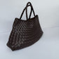 Dark brown woven PU handbag, angled front view showing the basket weave and two braided handles