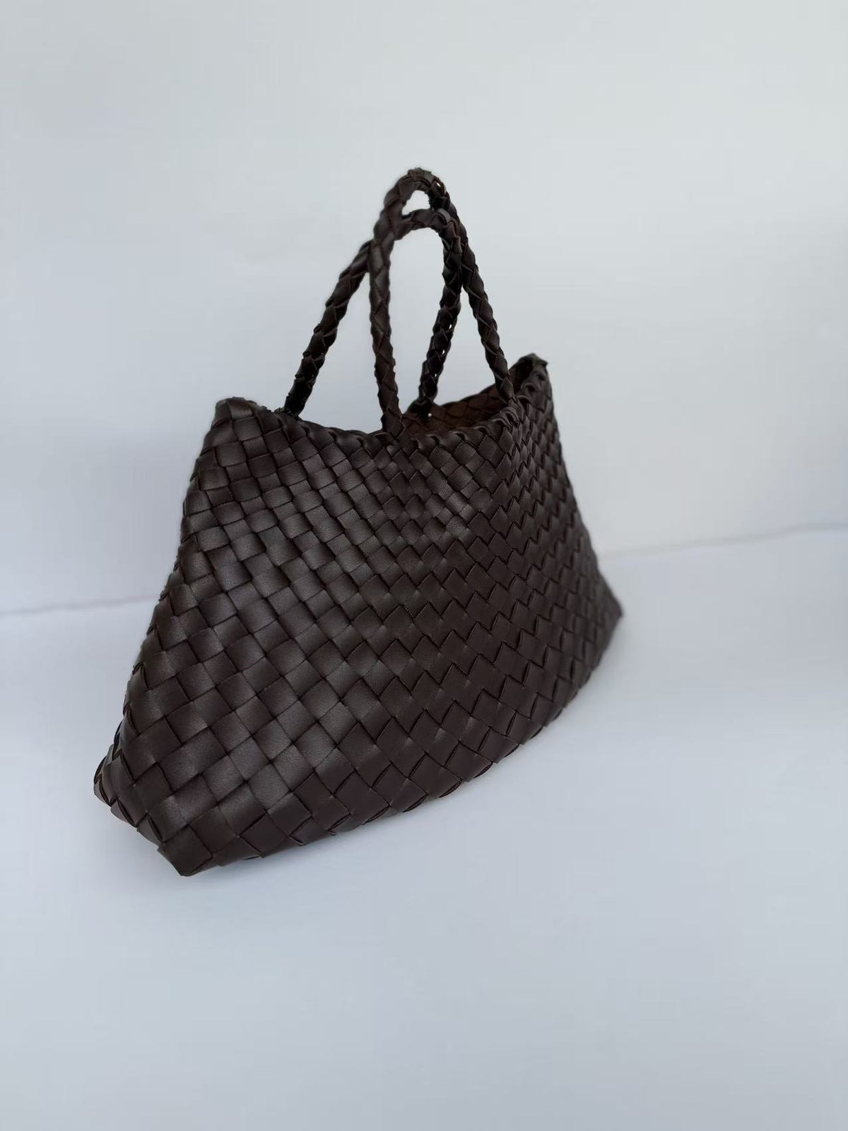 Dark brown woven PU handbag, angled front view showing the basket weave and two braided handles