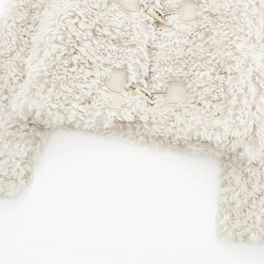 Detail of the cropped hem and toggle front on a cream curly fleece jacket