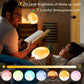 Man reading beside a child with the round wake-up light glowing warm in a dark bedroom