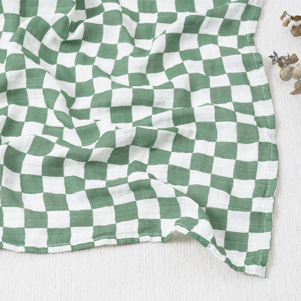 Large cotton muslin gauze baby blanket laid out, showing the loose breathable weave and print