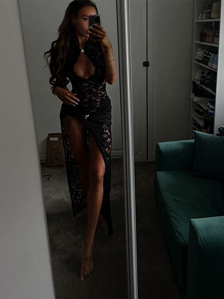 Mirror photo of a woman wearing the black lace maxi dress with keyhole collar and high thigh slit beside a green sofa