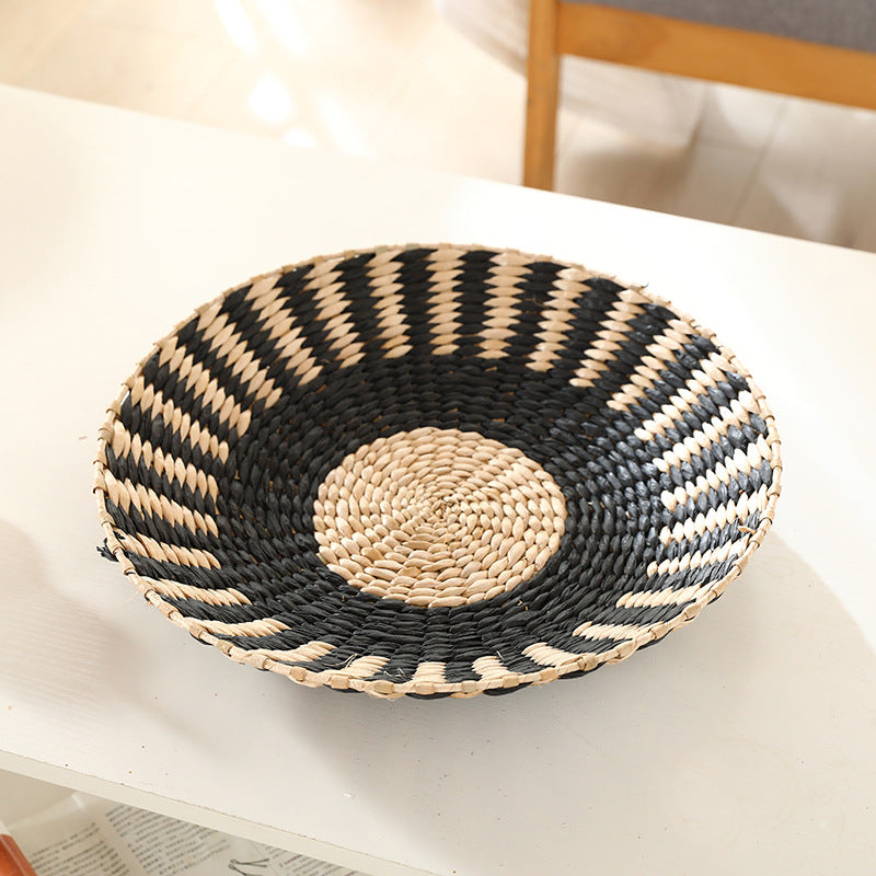 Shallow woven straw wall disc striped in black and natural grass fiber