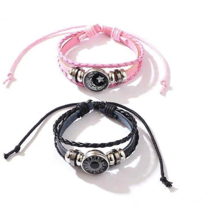 Pink braided cord bracelet with a glowing moon and star charm on a light surface