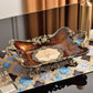 Scalloped footed resin fruit plate with gold tone scroll handles and a cream pearl shell center panel