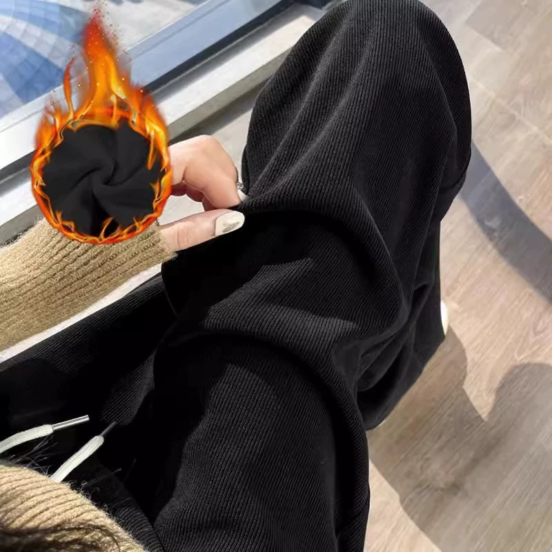 Black wide-leg pants with the cuff turned up to show black fleece lining, with a fleece icon, seen from the side