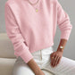 Woman wearing a pink half-high neck pullover sweater with long sleeves and ribbed cuffs seated on a sofa
