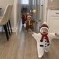 Toddlers in knitted Christmas outfits walking down a hallway, snowman and gingerbread styles shown