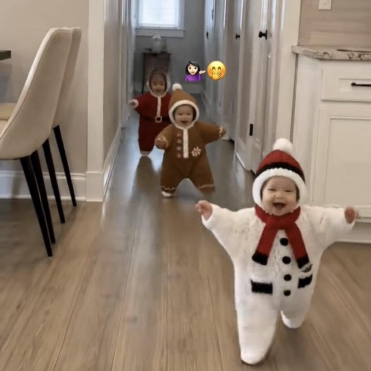 Toddlers in knitted Christmas outfits walking down a hallway, snowman and gingerbread styles shown