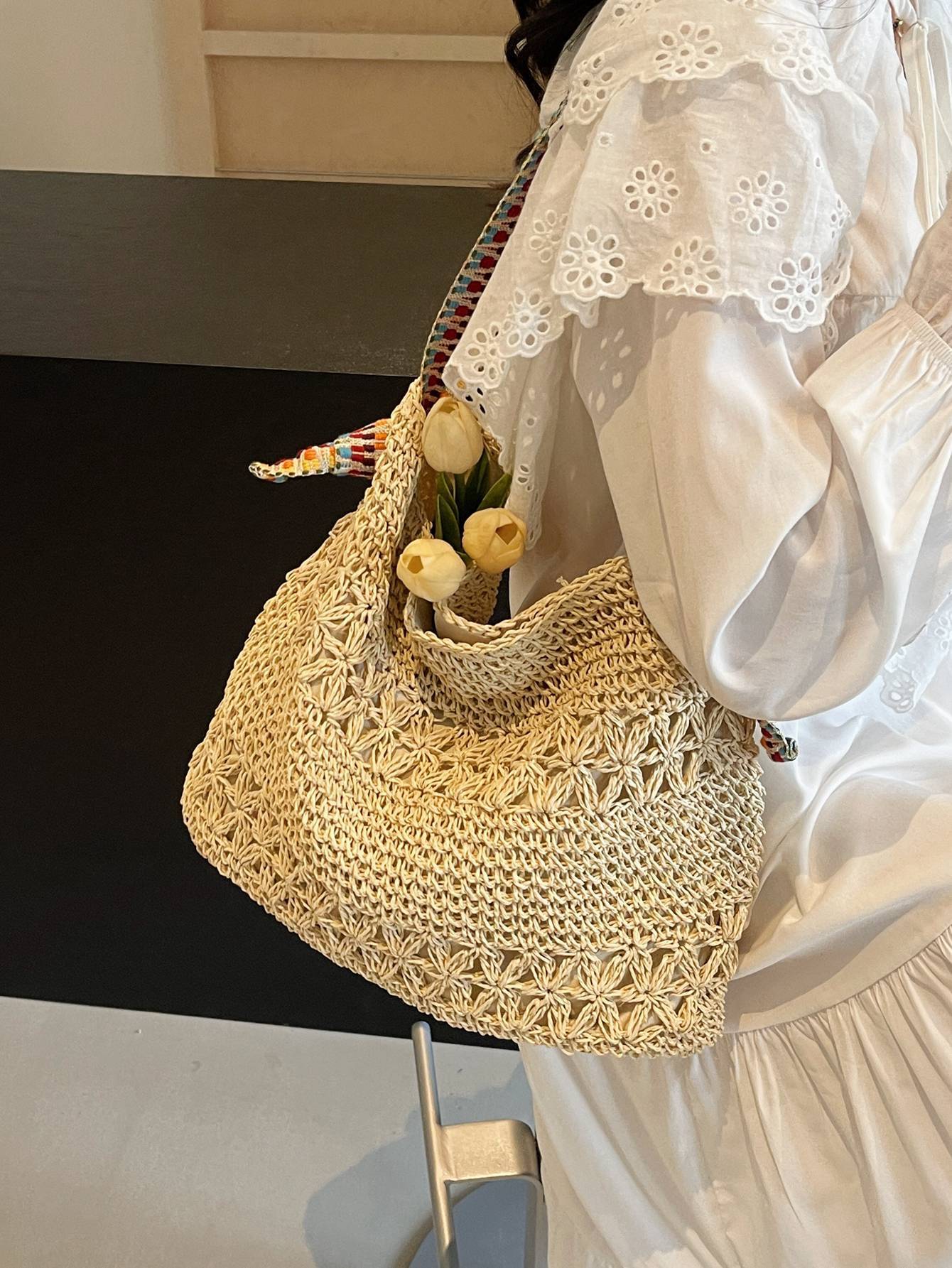 Beige straw shoulder tote with tulips and colorful woven strap on the shoulder