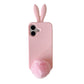 Light pink silicone rabbit iPhone case with ears and pom pom tail on a plain background