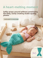 Newborn wearing the teal crochet mermaid tail, pink shell top and flower headband, posed on a small prop bed