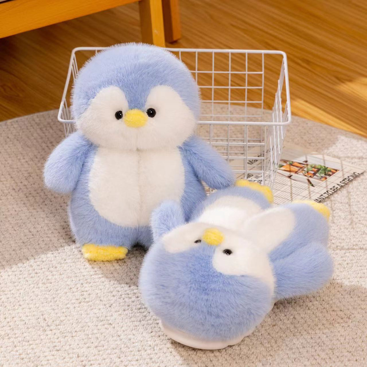 Blue plush penguin toy and a blue penguin slipper lying beside a wire basket on a round beige rug