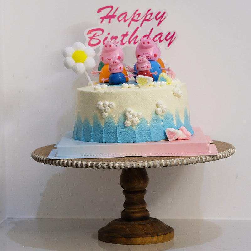 Birthday layer cake displayed on the wooden pedestal cake stand against a white wall