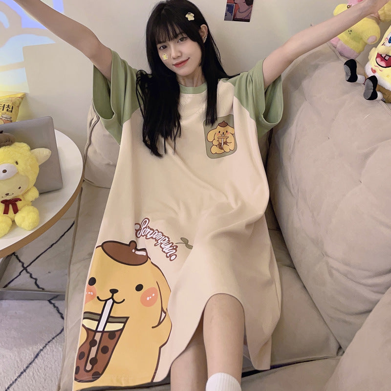 Woman raising both arms on a sofa in a cream short sleeve nightgown with green sleeves and a yellow dog print on the hem