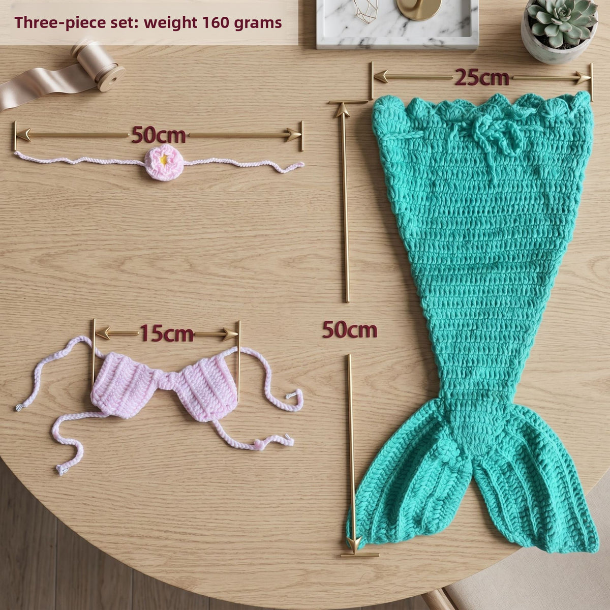 Teal crochet mermaid tail and pink shell top shown flat with measurement guides on a wood table