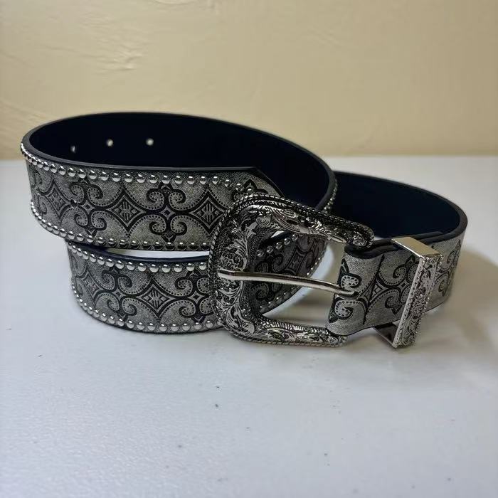 Close view of the studded edges and embossed scroll pattern on the grey western belt