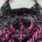 Close view of the black lace shoulder panel, halter ties and rhinestone lettering on the black and pink top