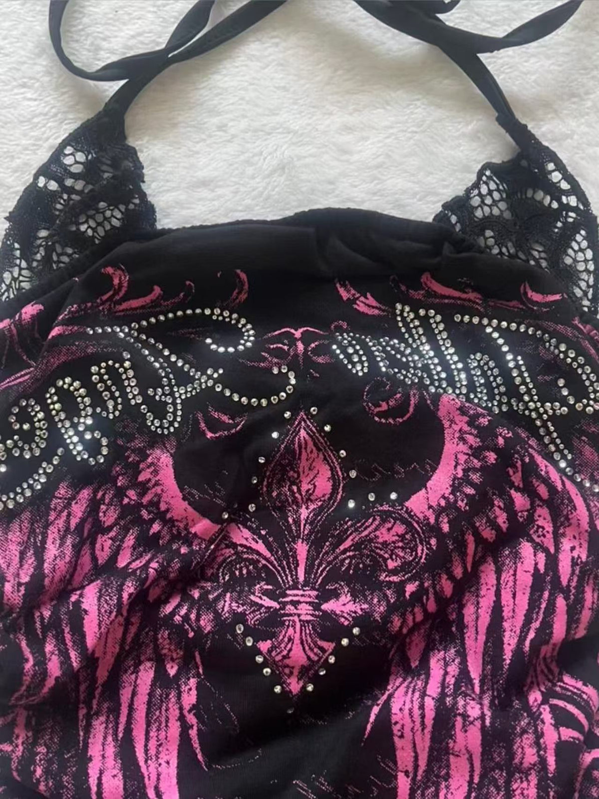 Close view of the black lace shoulder panel, halter ties and rhinestone lettering on the black and pink top