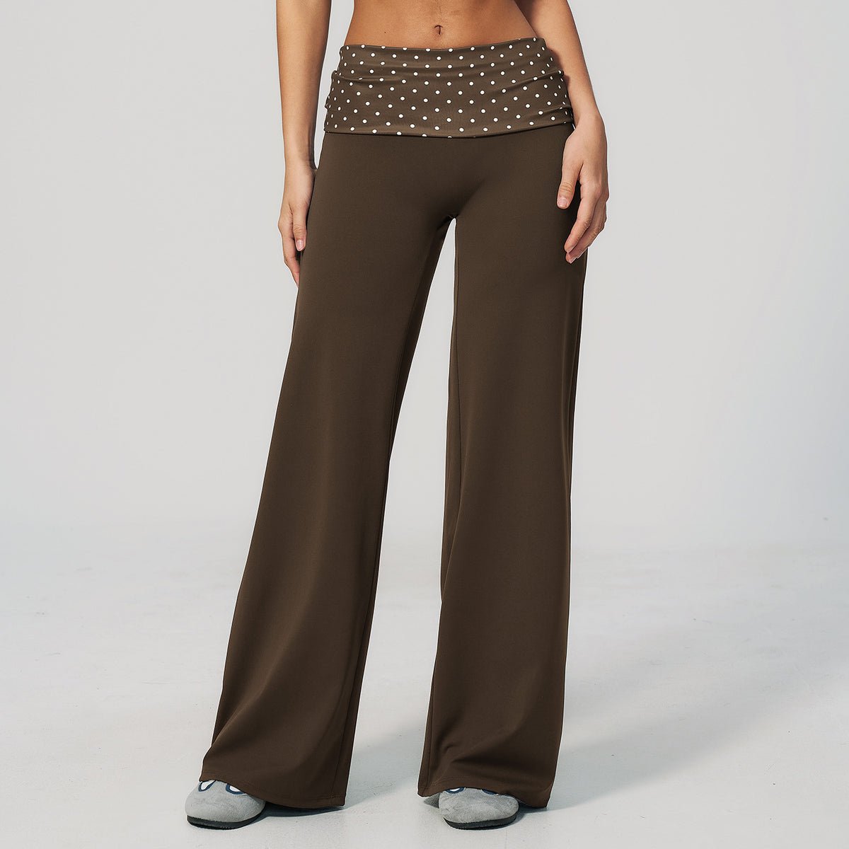 Model in wide leg pants with a fold over printed waistband, brown with white polka dots