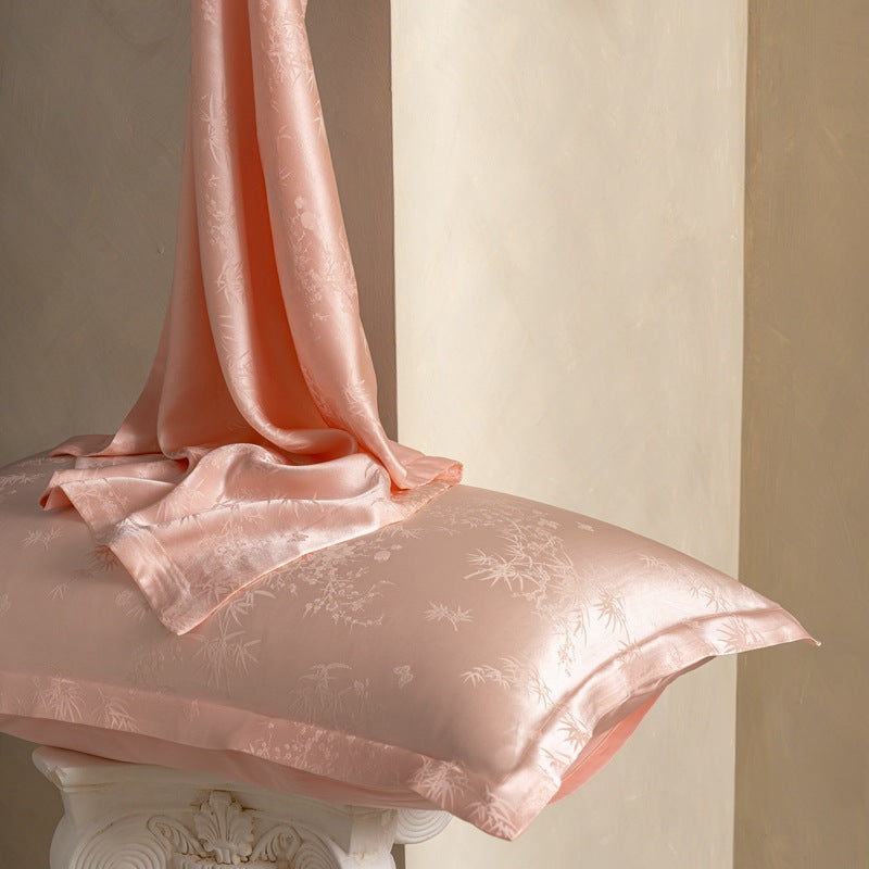 Birds And Flowers Pink jacquard silk pillowcase in pink with silk draped over it, pair option