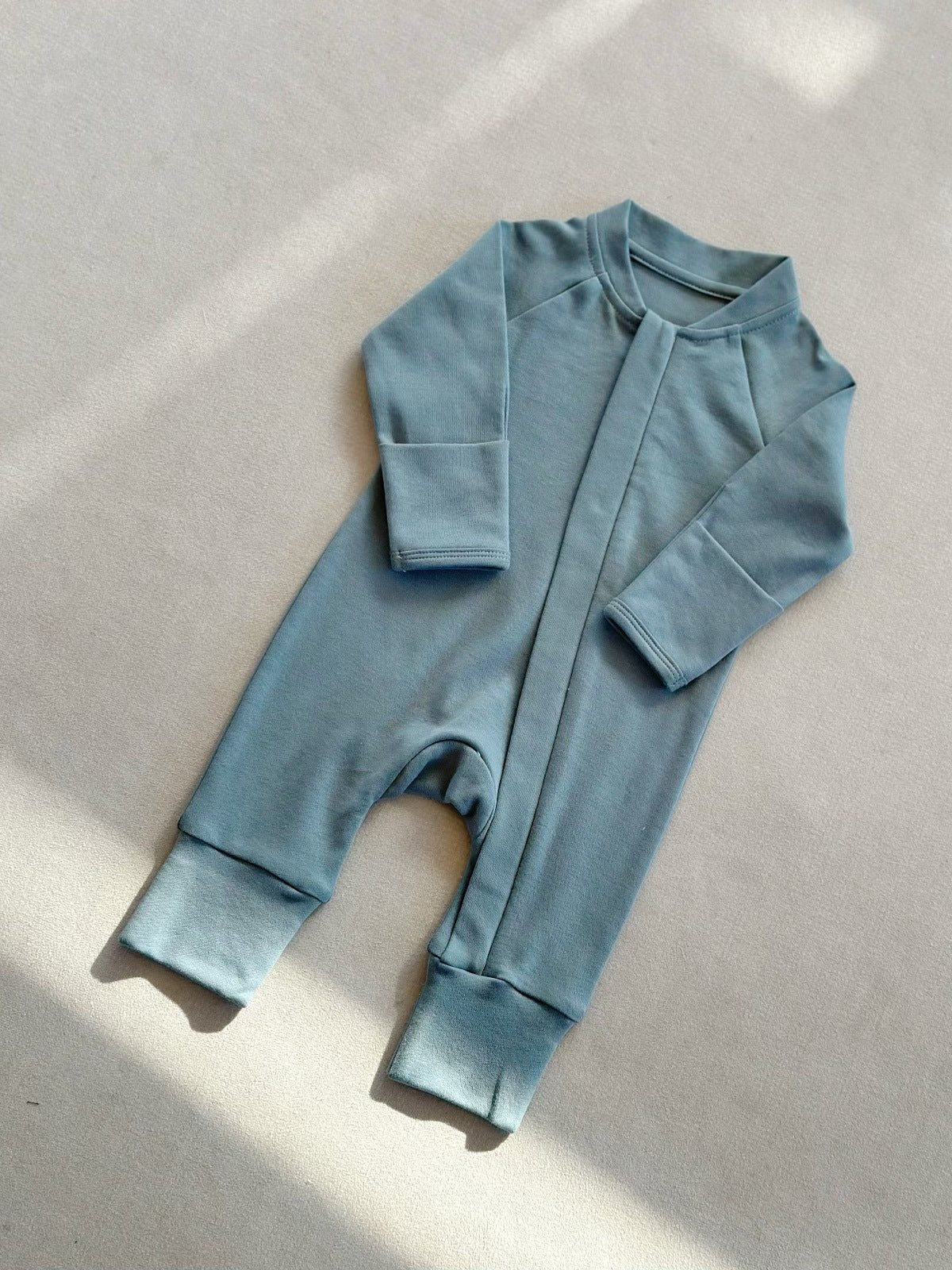Hazy Blue zip front baby romper laid flat on a gray floor, image of the 59 cm, 0 to 3 months size option