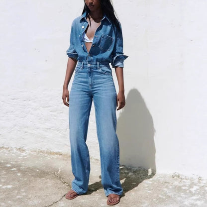Women's washed denim jumpsuit with collar and button front worn full length on a model against a white wall