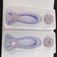 Two lilac cotton thread facial hair removers in trays with their round holders beside them