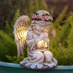Praying angel resin garden statue with flower crown glowing warm at dusk on a planter edge