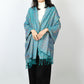 Woman wearing a turquoise blue paisley shawl open over the shoulders with matching turquoise tassels
