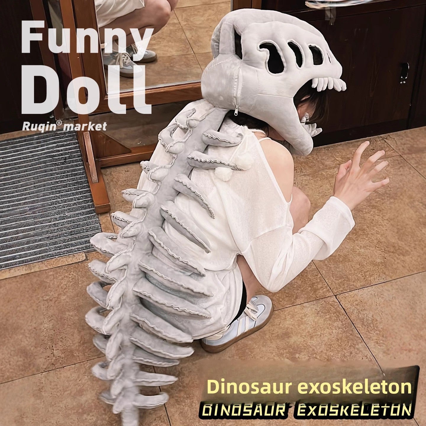 Gray plush dinosaur exoskeleton costume hood and long spine tail draped over a person kneeling on tiles