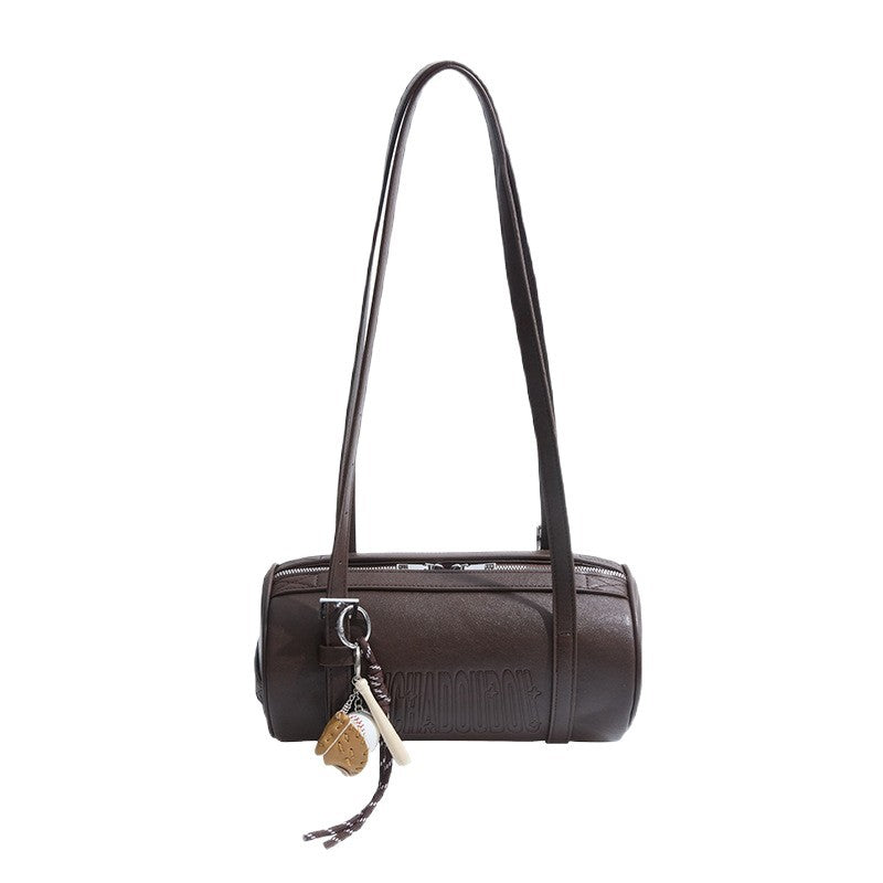 Coffee brown cylinder shoulder bag with two long straps and a baseball glove charm on a white background