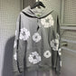 Grey cotton wreath print hoodie on a hanger showing the front pocket and hood