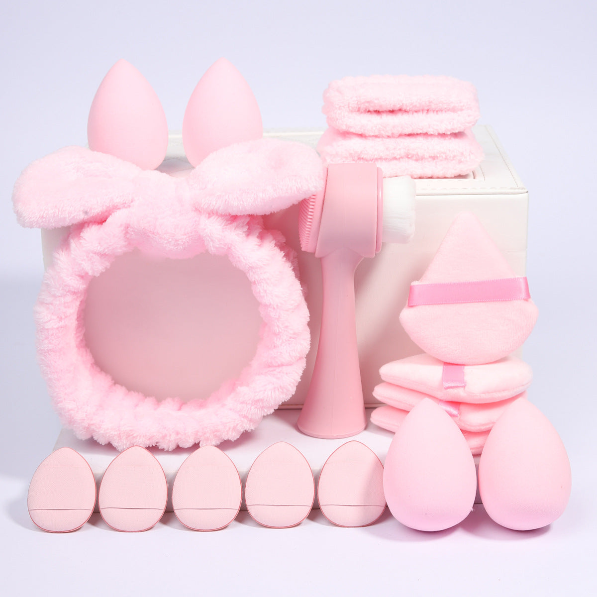Row of foam makeup sponges and velvet powder puffs laid out by color