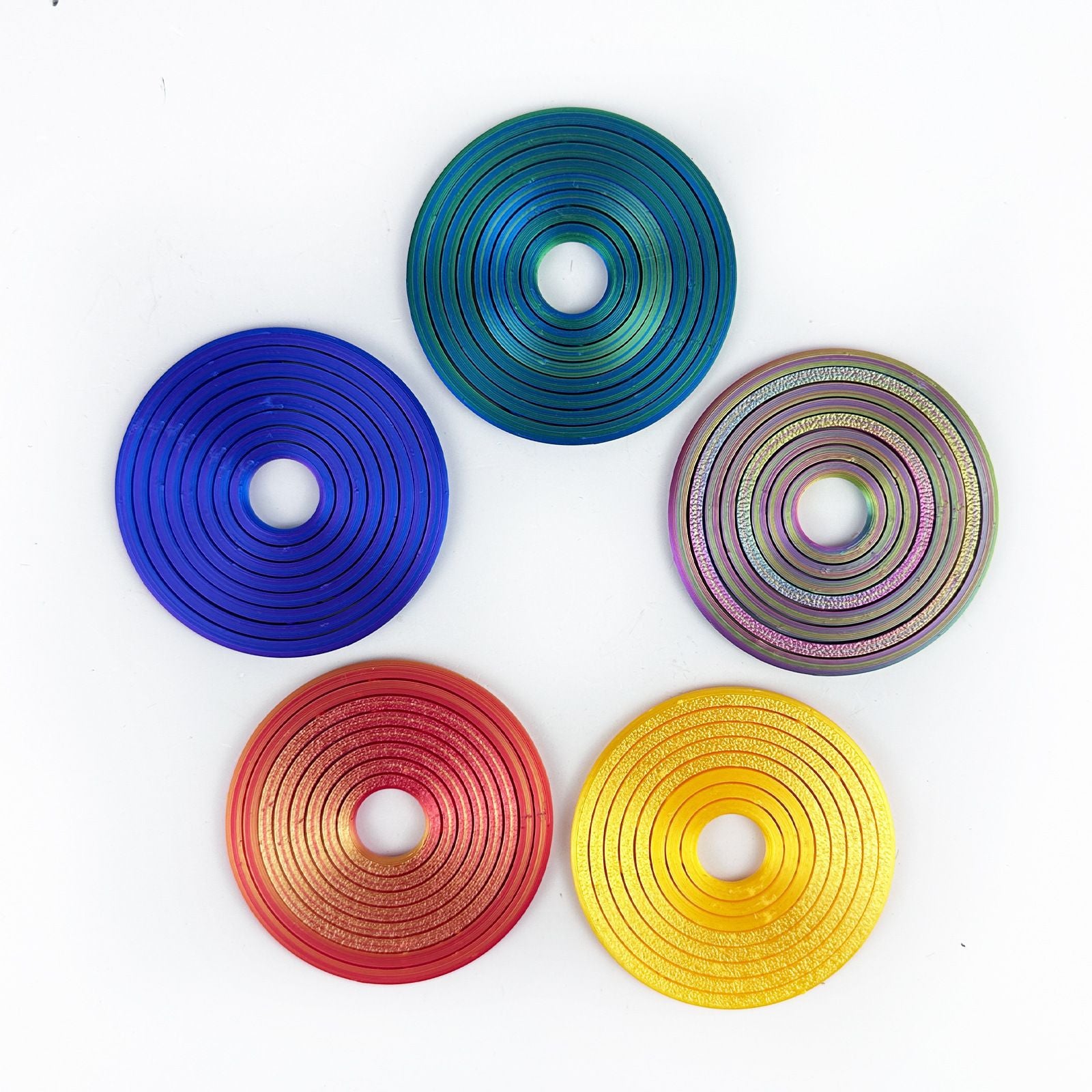 Five flat gyro ring discs arranged in a circle showing the five printed finishes
