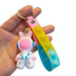 Astronaut rabbit keychain with a molded spacesuit body and long ears on a pastel silicone pop strap