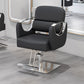 Gray salon styling chair with curved silver armrests on a silver disc base in a salon