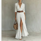Woman in a white long shirt dress with collar, brown belt and a high front slit, full length front view