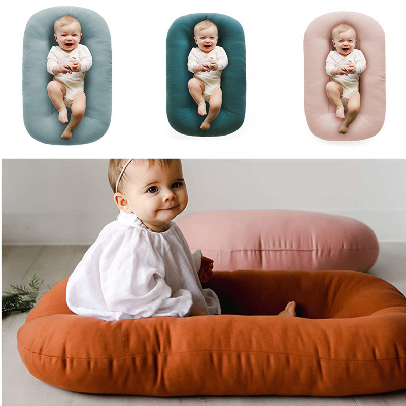 Padded baby lounger nests in blue teal and pink each with a baby resting in the center