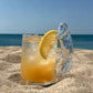 Clear hand blown glass mug with sculpted novelty handle filled with water outdoors