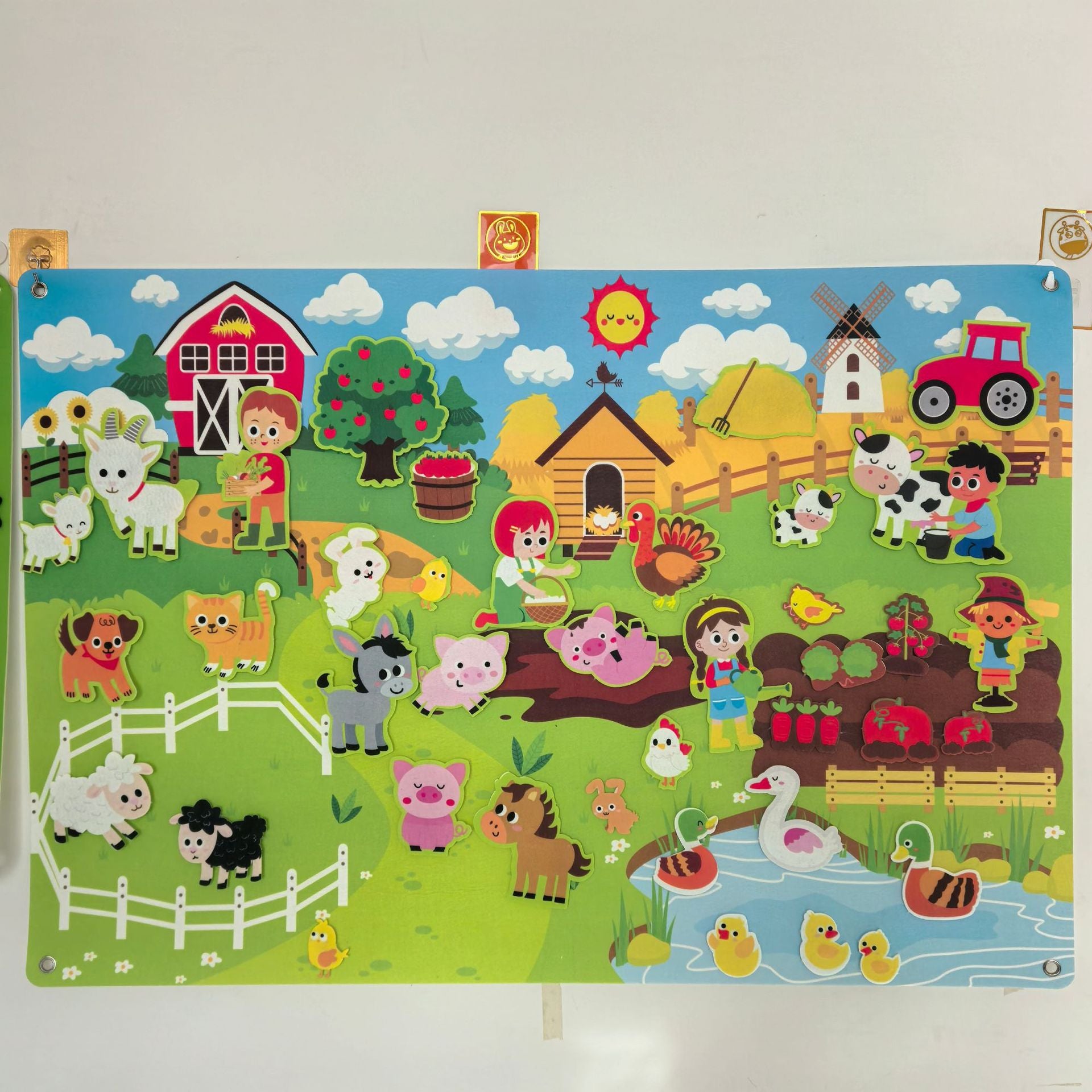 Farm felt story board hung on a wall with felt barn, animals and pond pieces in a childs room