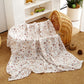Folded cotton muslin swaddle blanket with a soft open weave and an even printed pattern