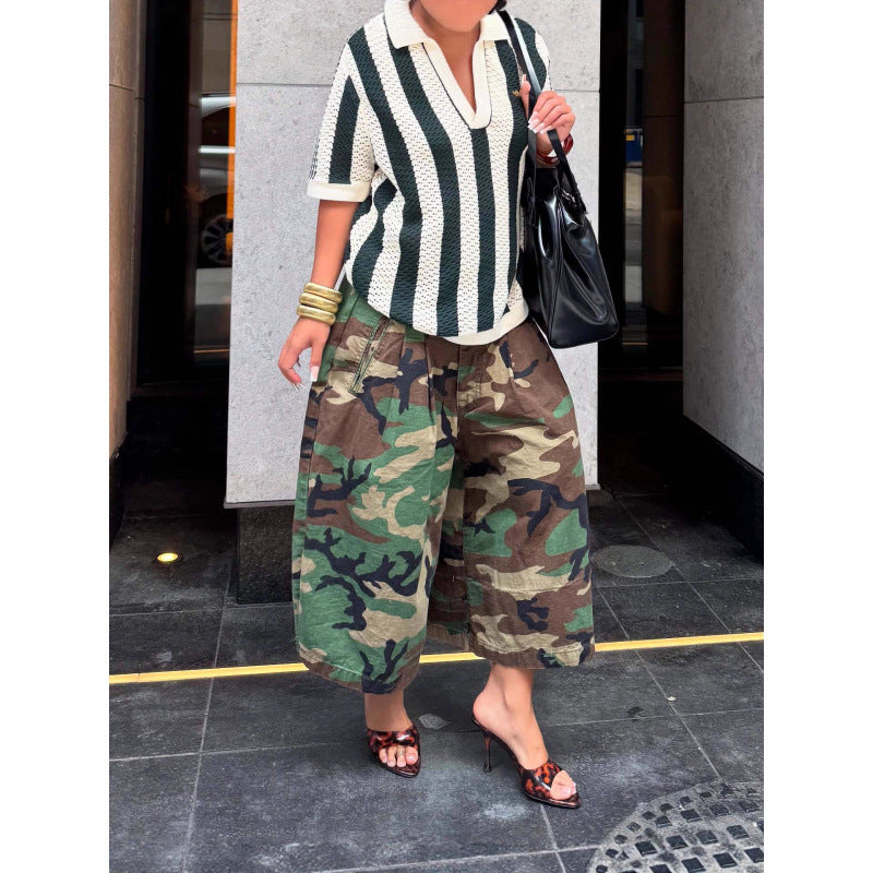 Green camouflage wide-leg pants worn with a green and white striped top, hands near the waistband, front view
