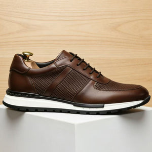 Chocolate brown cowhide leather sneaker, side profile on a white plinth against pale wood
