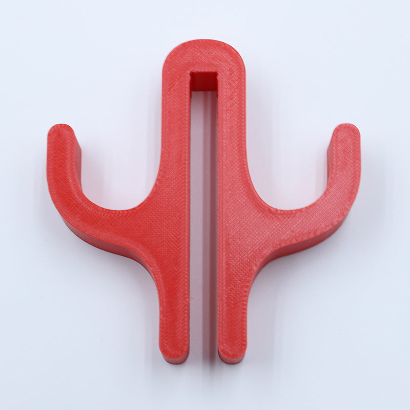 Red resin double hook with an arm on each side, seen from the front on a light background