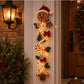 Gingerbread Christmas door hanger with Santa hat, candy canes and glowing lights beside a porch lantern