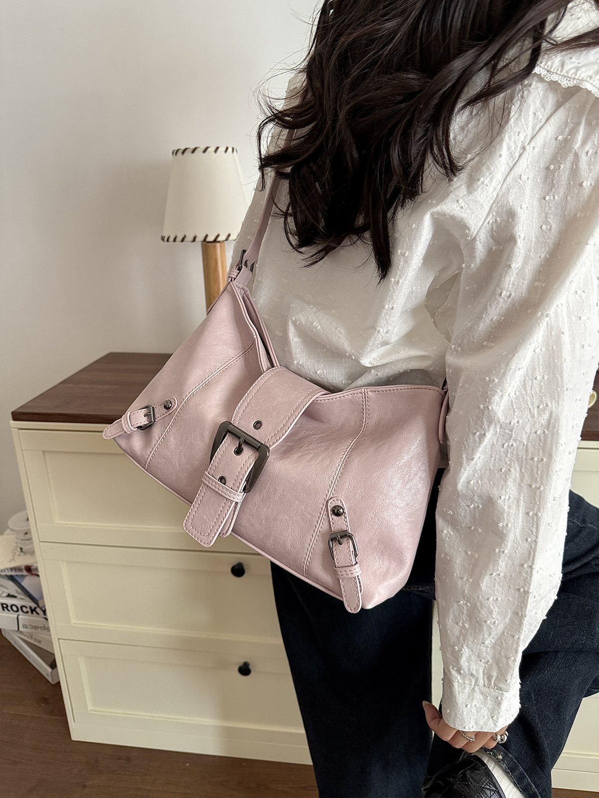 Pink soft vegan leather hobo bag with front buckle strap worn over the shoulder with a white blouse