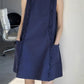 Navy A-line dress showing round neck, ruffle trims and two front patch pockets