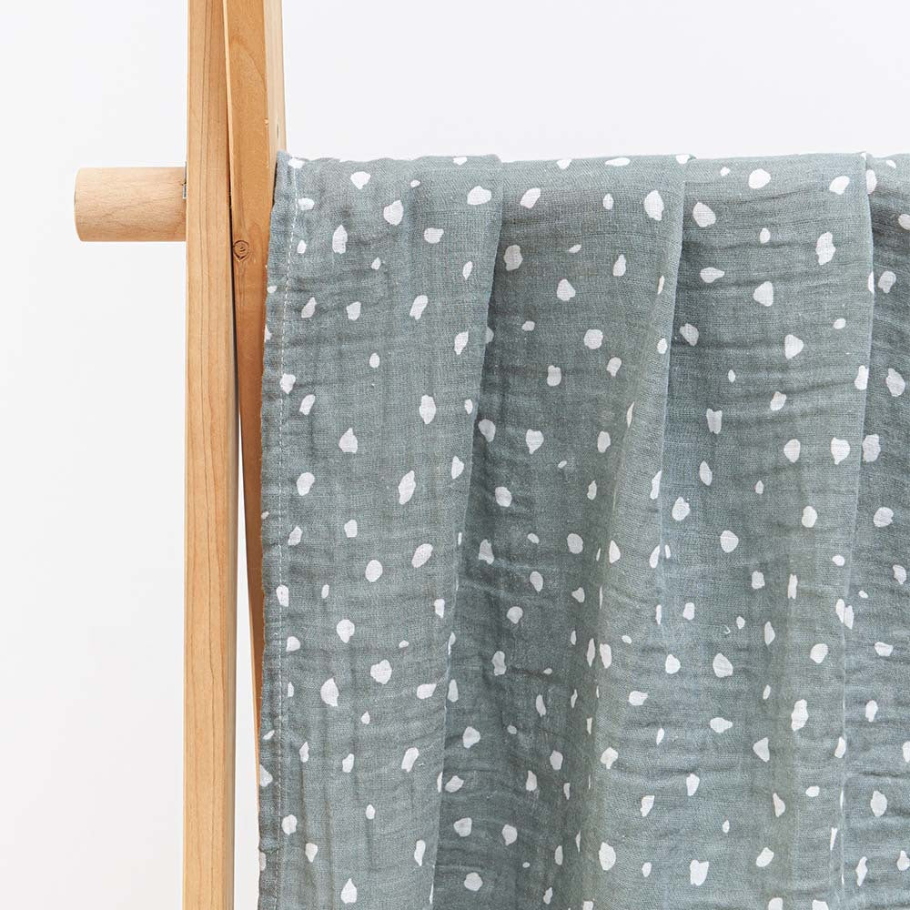 Folded cotton muslin swaddle blanket with a soft open weave and an even printed pattern