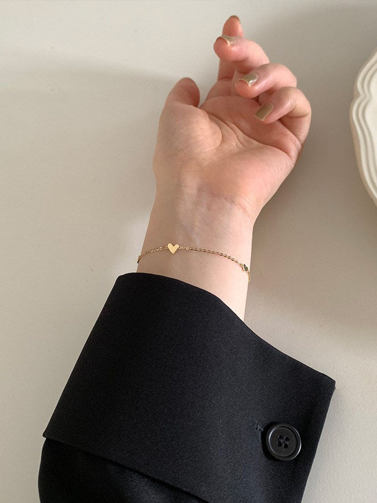 Heart bracelet worn on the wrist during a daily moment, paired with a soft cuff